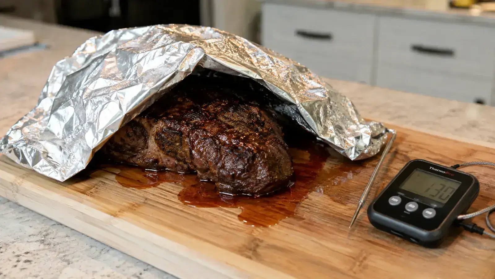 A rested steak tented loosely with foil on a cutting board with visible juices pooling around it